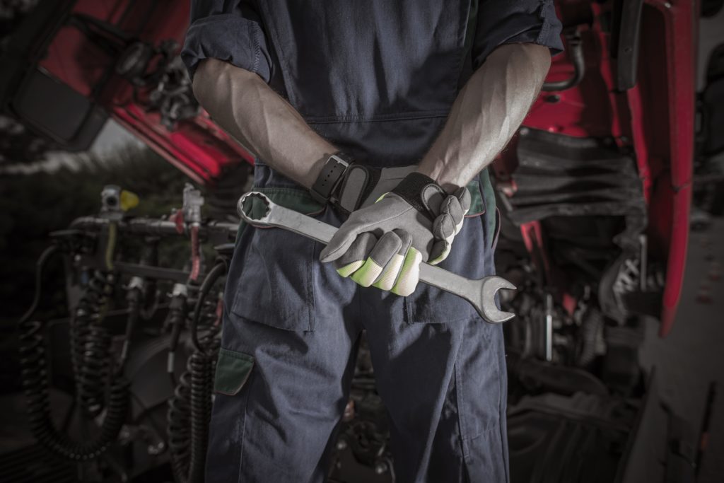 technician holding wrench behind his back in repair shop
